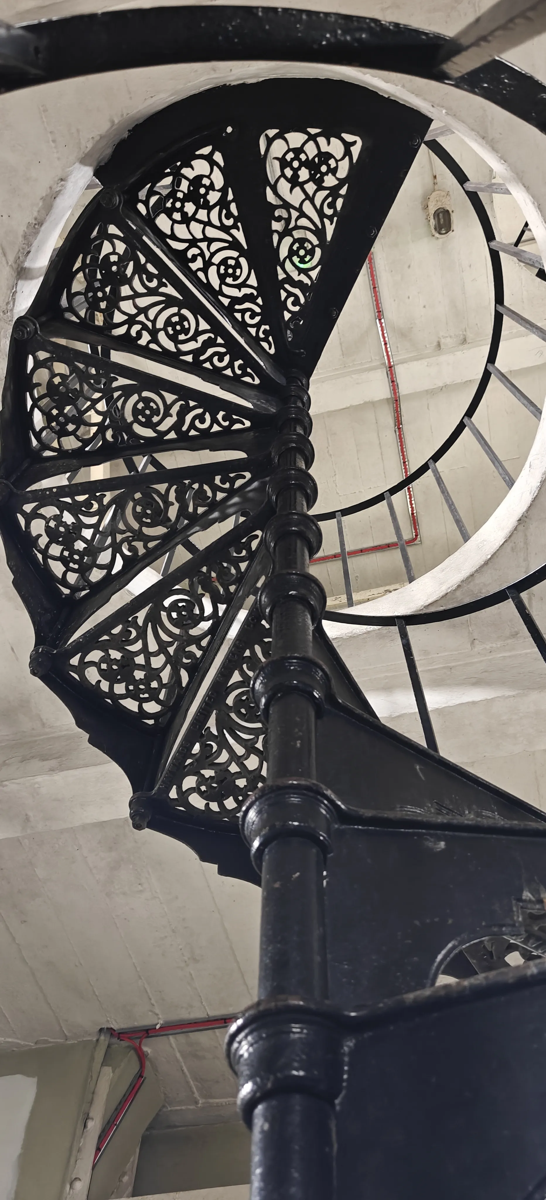 An ornate black cast-iron spiral staircase rising through the clock tower